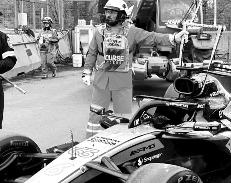 Sam en équipe de récupération sur un circuit de Formule 1, dirigeant la grue devant une monoplace